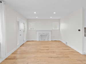 Unfurnished living room with light wood finished floors, recessed lighting, and healthy amount of natural light
