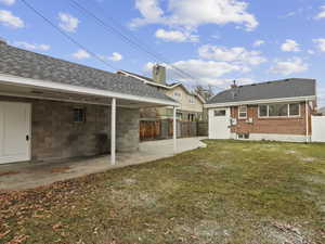 Back of property with a patio, a shingled roof, brick siding, and a chimney