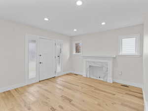Unfurnished living room with light wood finished floors, recessed lighting, and a high end fireplace