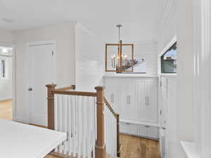 Stairway featuring wood walls, a chandelier, and wood-type flooring
