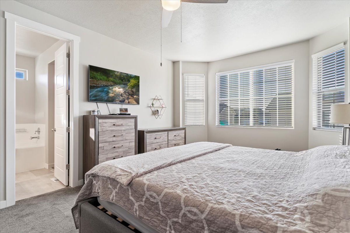 Bedroom with multiple windows, carpet, a ceiling fan, and a textured ceiling