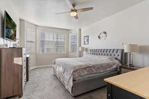 Carpeted bedroom featuring ceiling fan and a textured ceiling