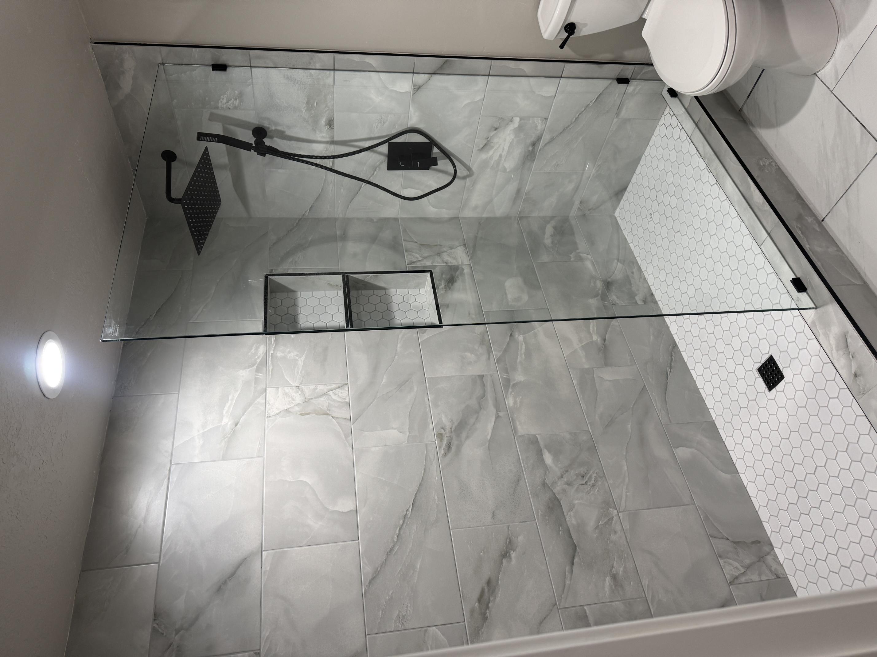 Bathroom featuring walk in shower, light marble finish floors, and recessed lighting