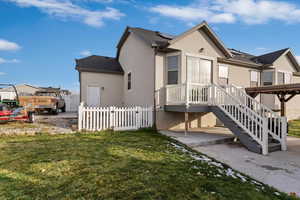 Rear view of property featuring stucco siding, solar panels, and a wooden deck