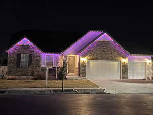 View of front of property with stone siding, concrete driveway, and a garage