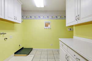 Laundry area with cabinet space, light tile patterned flooring, and hookup for a washing machine