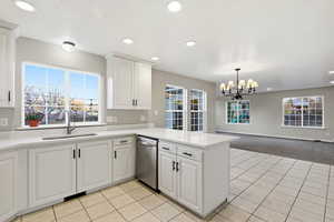 Kitchen featuring white cabinetry, open floor plan, light colored carpet, stainless steel dishwasher, and recessed lighting
