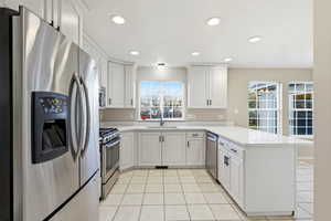 Kitchen featuring appliances with stainless steel finishes, white cabinets, a peninsula, recessed lighting, and light tile patterned floors