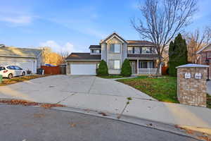 Traditional-style house with a porch, concrete driveway, and a garage