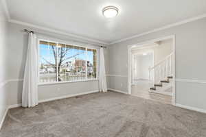 Unfurnished room with stairs, light colored carpet, and ornamental molding