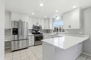 Kitchen featuring stainless steel appliances, white cabinets, a peninsula, light tile patterned floors, and recessed lighting
