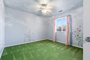 Carpeted empty room with a textured ceiling and a ceiling fan