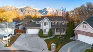 Traditional home with a porch, a mountain view, concrete driveway, and brick siding