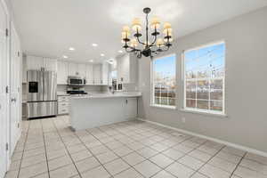 Kitchen with white cabinets, stainless steel appliances, a chandelier, recessed lighting, and hanging light fixtures