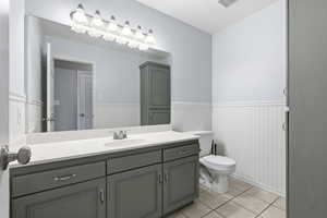Bathroom with vanity, wainscoting, and light tile patterned flooring