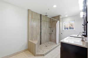 Bathroom featuring a shower stall, double vanity, light tile patterned floors, and recessed lighting