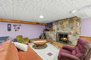 Living room featuring concrete block wall and a stone fireplace