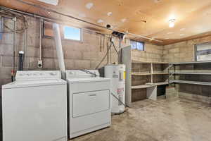 Laundry room featuring concrete floors, water heater, and separate washer and dryer