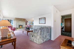 Carpeted living area with a stone fireplace