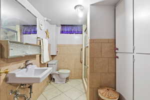 Full bathroom with tile walls, light tile patterned floors, and a stall shower