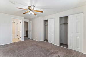 Unfurnished bedroom with multiple closets, carpet flooring, a ceiling fan, and a textured ceiling