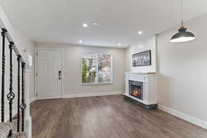 Foyer with stairway, dark wood-style floors, a fireplace, and recessed lighting