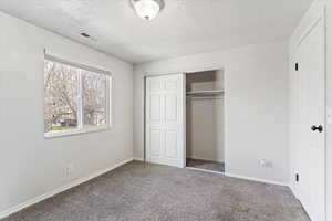 Unfurnished bedroom featuring a closet, carpet flooring, and a textured ceiling