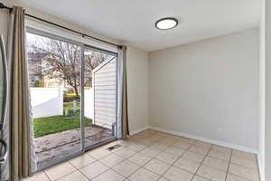 Empty room featuring baseboards and light tile patterned floors