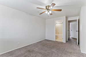 Unfurnished bedroom with carpet floors, a textured ceiling, a ceiling fan, and ensuite bathroom