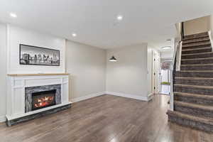 Unfurnished living room featuring wood-type flooring, a fireplace, and stairs