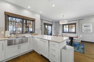 Kitchen with white cabinetry, dark wood finished floors, decorative light fixtures, backsplash, and recessed lighting