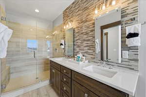 Bathroom with double vanity, a stall shower, and tile walls