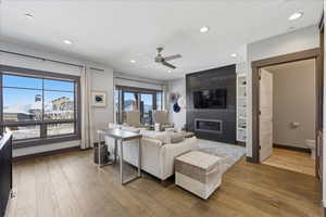 Living area with light wood-type flooring, a fireplace, ceiling fan, a textured ceiling, and recessed lighting