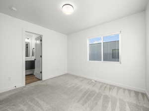 Unfurnished bedroom with light colored carpet and ensuite bathroom