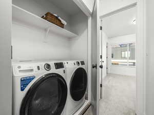 Washroom featuring light colored carpet and washer and dryer