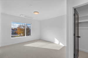 Unfurnished bedroom featuring light colored carpet and a walk in closet