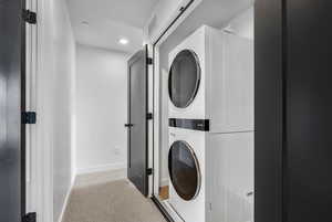 Washroom with stacked washer and clothes dryer, recessed lighting, and carpet