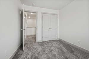 Unfurnished bedroom featuring dark carpet and a closet