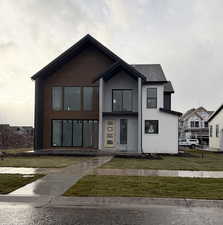 View of front of house with a front lawn and roof with shingles