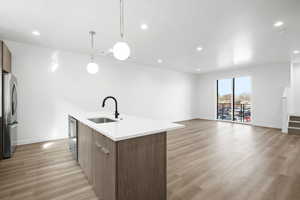 Kitchen with hanging light fixtures, modern cabinets, brown cabinetry, stainless steel appliances, and recessed lighting