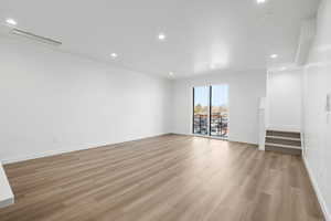 Spare room with stairway, light wood-style floors, and recessed lighting