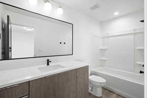 Bathroom featuring vanity, tub / shower combination, and dark wood-style floors
