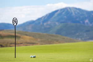 View of community featuring a mountain view, a lawn, and view of golf course