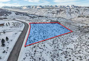 Snowy aerial view featuring property boundaries highlighted and a mountain view