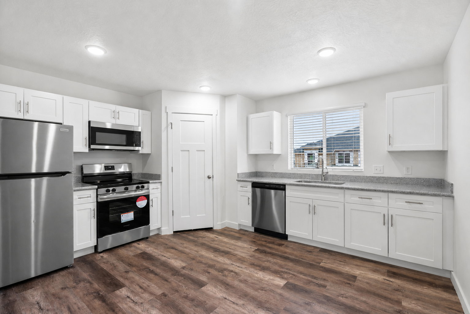 Kitchen featuring stainless steel appliances, white cabinetry, dark wood-style flooring, and recessed lighting