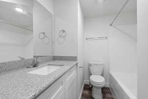 Bathroom featuring vanity, tub / shower combination, and dark wood-style floors
