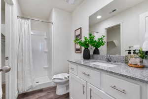 Full bath with a shower stall, vanity, and dark wood-type flooring