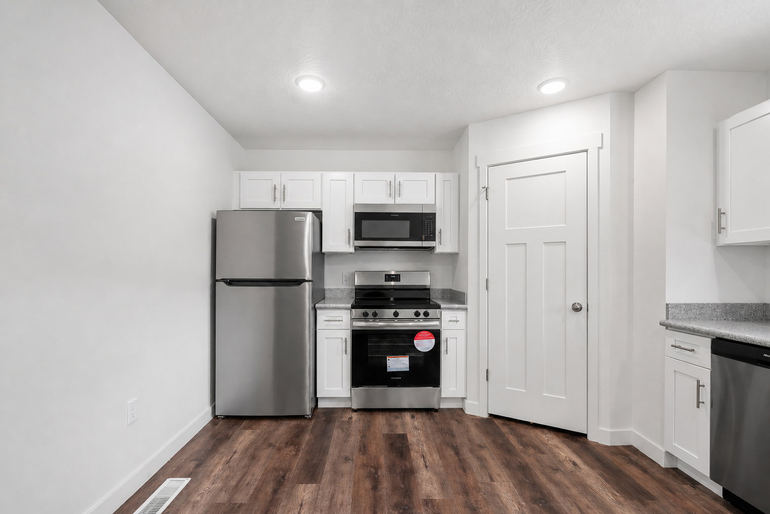 Kitchen featuring stainless steel appliances, white cabinets, and dark wood finished floors