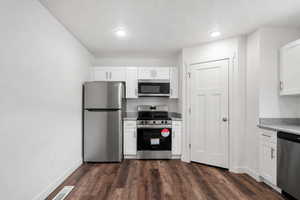 Kitchen featuring stainless steel appliances, white cabinets, and dark wood finished floors