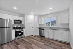 Kitchen featuring stainless steel appliances, white cabinets, dark wood-style flooring, and recessed lighting